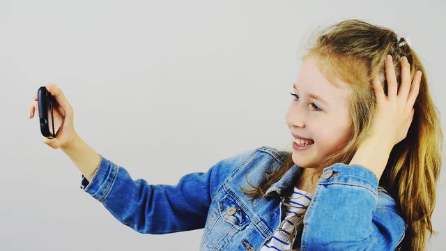 Happy little girl taking selfie with mobile phone.