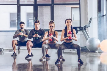  Group of athletic young people in sportswear with dumbbells exercising at the gym © LIGHTFIELD STUDIOS
