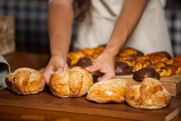 Mid-section of woman holding bread at counter