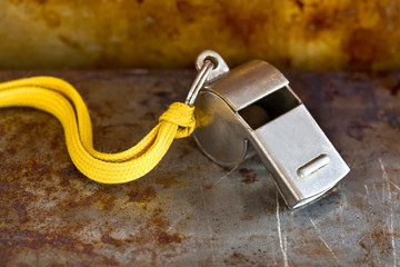 Vintage silver whistle on rusty metallic background. Referee trainer sport competition tool...