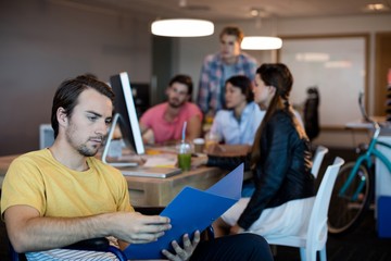 Physically disabled man on wheelchair reading a file in office