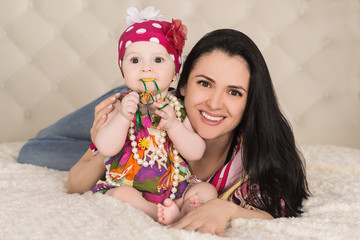portrait of cute baby girl with mother on the bed, indoors
