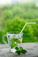 Drink with lemon and mint in a glass with straws