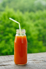 Carrot juice in glass bottles with straws.
