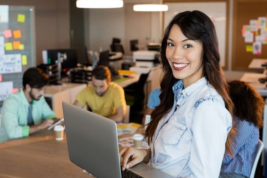 Smiling woman using laptop at office