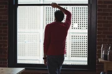 Thoughtful man looking through window at home