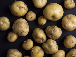 New small, round summer potatoes in a pile isolated on black background