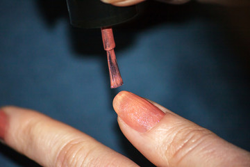 A woman applying her nails in a light brown color polish