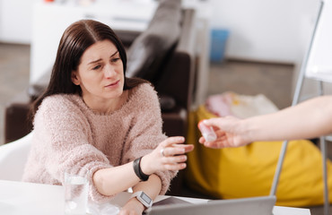 Sick woman stretching her hand to the medicine