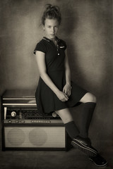 Vintage portrait of a girl. An old radio set is used as decoration.