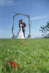 Bride and groom standing by an arch, ocean view