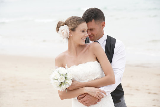 Portrait of happy bride and groom embracing each other at the beach