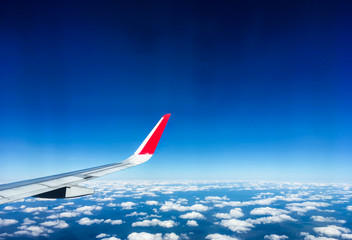 Fototapeta na wymiar Clouds on Deep Blue Sky and airplane wing, view form airplane window, travel concept with copyspace