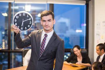 Businessman stading and holding clock with team while meeting, Businessman leader concept, 20-30...