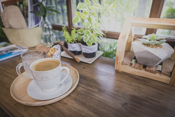 Cup of hot coffee in circle wooden tray on wooden counter in coffeeshop