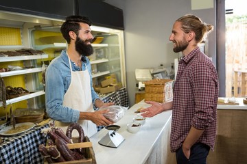 Smiling customer receiving packed meat at counter