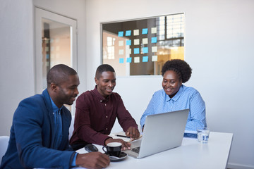 Smiling young African businesspeople using a laptop in an office