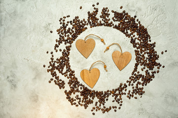 Circle silhouette made from coffee beans with three wooden heart tags inside and copy space at the side, top view