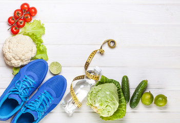 Fresh healthy vegetables, sneakers on white wood background.