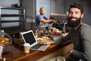Male customer using laptop while having coffee 