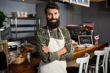 smiling male staff standing with arms crossed