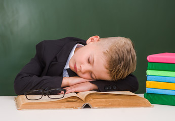 Boy sleeping on book in classroom