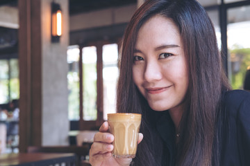 A beautiful Asian woman holding and drinking hot coffee with feeling good in vintage cafe