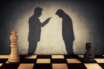 Chess pawn and king standing in front one another with their shadow transform into businessman...