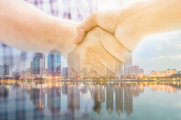 Double exposure of two Asian people make handshake whit some success story in teamwork concept