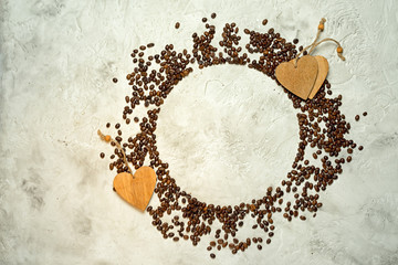 Circle silhouette made from coffee beans with wooden heart tags and copy space, top view. Might be used as pie chart about coffee consumption.