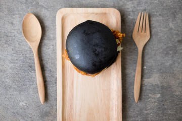 Black burger on wooden background. Meat and lettuce leaves