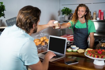 Customer receiving a coffee from staff at counter 