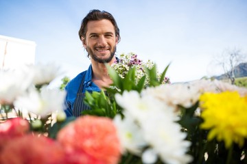 Fleuriste souriant tenant un bouquet de fleurs dans une boutique de fleuriste