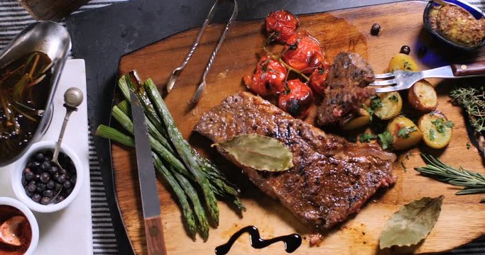 Dolly top down view of a delicious sirloin steak with asparagus, potatoes and roasted tomatoes