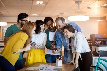 Smiling creative business team using mobile phone in office
