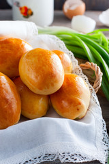 Oven fresh home made baked patties stuffed with eggs and green onion on rustic wooden background. Home cuisine. Close up delicious stuffed home cooking pastries on an orange plate and napkin.