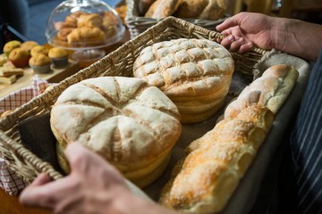Male staff holding a basket of bread
