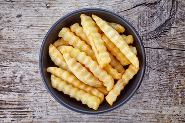 Bowl of french fries on wood, from above