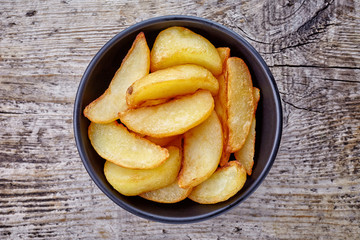 Bowl of potato wedges on wood, from above