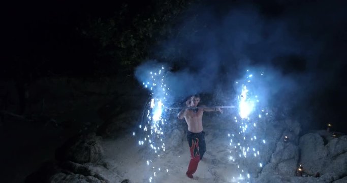 Aerial view of handsome man doing fires how at the beach - video in slow motion