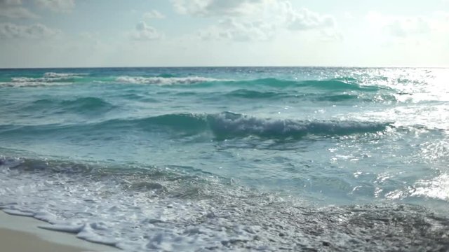 Blue waves coming in on shore sand.
