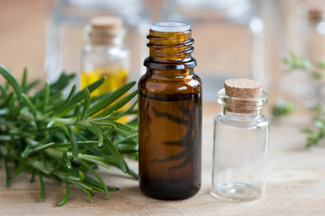 A bottle of rosemary essential oil with fresh rosemary twigs