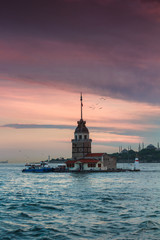 Fototapeta premium Beautiful landscape of Maiden's tower (Tower of Leandros) at sunset. Dramatic cloudy sky. In the distance are such landmarks as Hagia Sophia, Blue Mosque and Topkapi Palace. Istanbul. Turkey.