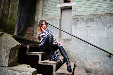 Fashionable woman look with black and white striped suit jacket, leather pants, posing at old...