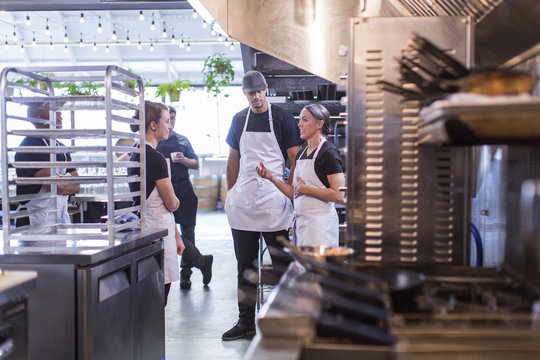 Female chef discussing with coworkers in restaurant kitchen