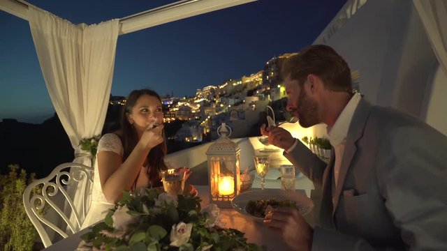 4k video honeymoon couple enjoying private luxury candle light dinner oustide on terrace in Thira
