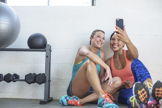 Happy female friends taking selfie through mobile phone in gym
