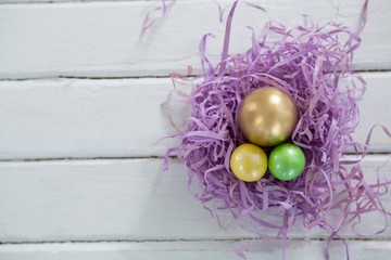 Golden Easter egg with two painted eggs in nest