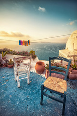 Abstract scene of two wooden chairs on a patio on Santorini, Greece.  - obrazy, fototapety, plakaty
