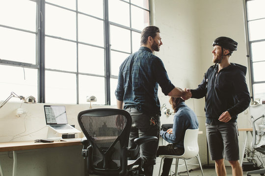 Businessman giving handshake to colleague in creative office
